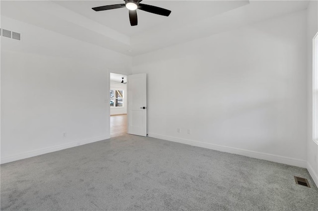 carpeted spare room featuring baseboards, visible vents, and a ceiling fan