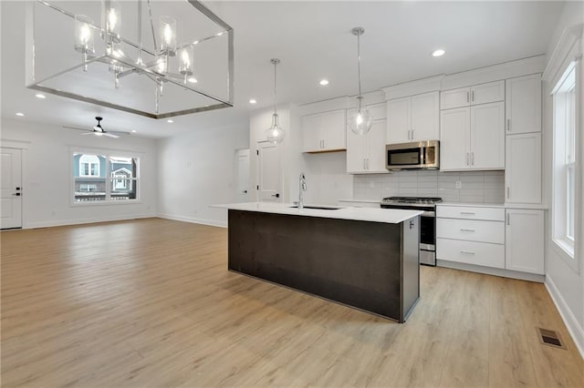 kitchen with tasteful backsplash, white cabinets, stainless steel appliances, light countertops, and a sink