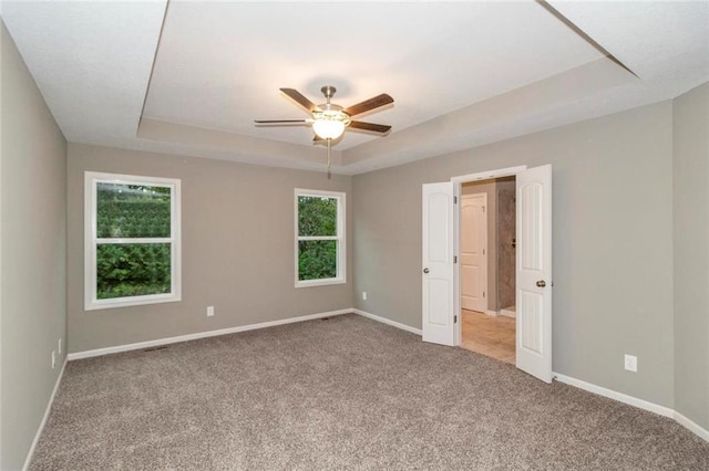 unfurnished room with carpet flooring, a tray ceiling, and ceiling fan