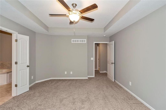 unfurnished bedroom featuring light carpet, ensuite bath, and ceiling fan