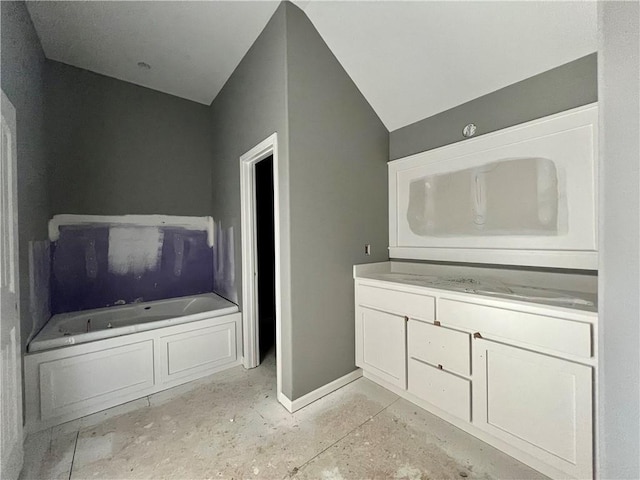 bathroom featuring a bathtub, lofted ceiling, and vanity