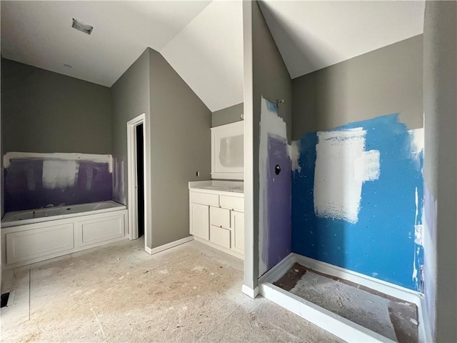 bathroom with vanity, a tub, and lofted ceiling