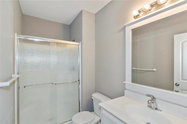 bathroom featuring vanity, an enclosed shower, and toilet