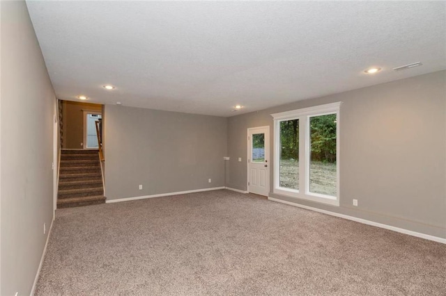 carpeted empty room featuring a textured ceiling