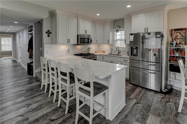 kitchen featuring dark hardwood / wood-style floors, a breakfast bar area, sink, white cabinetry, and stainless steel appliances