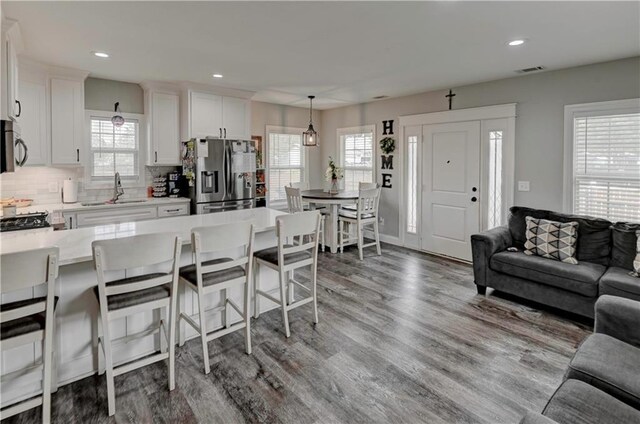 kitchen featuring stainless steel appliances, white cabinets, decorative light fixtures, and sink