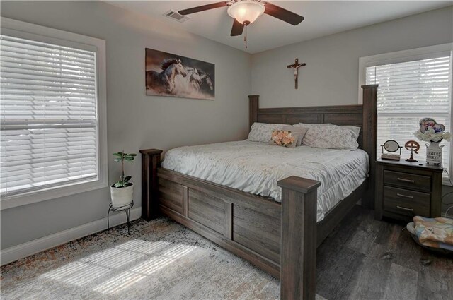 bedroom featuring multiple windows, dark hardwood / wood-style floors, and ceiling fan