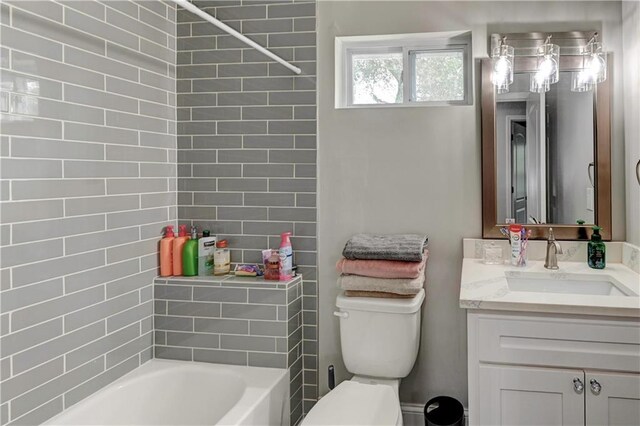 full bathroom featuring vanity, tiled shower / bath combo, and toilet