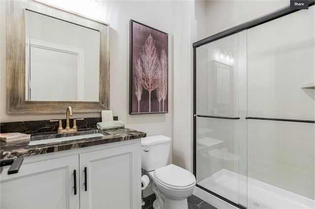 bathroom featuring tile patterned floors, vanity, toilet, and walk in shower