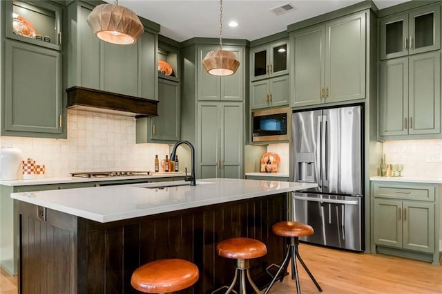 kitchen with sink, hanging light fixtures, stainless steel appliances, tasteful backsplash, and green cabinetry