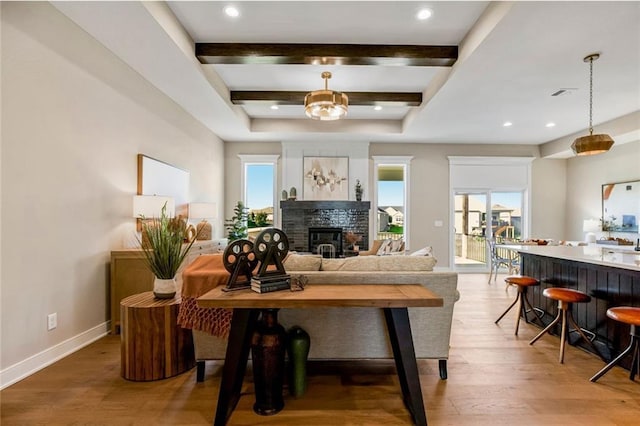 living room with a wealth of natural light, hardwood / wood-style floors, and beamed ceiling