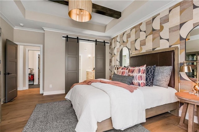 bedroom featuring a barn door, baseboards, wood finished floors, ensuite bathroom, and beam ceiling