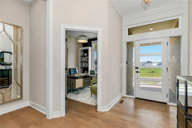 entryway with light wood finished floors, baseboards, and ornamental molding