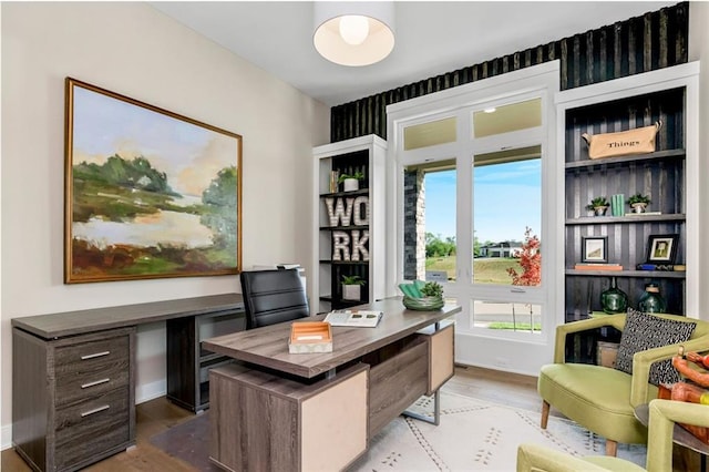 office area with baseboards, wood finished floors, and a healthy amount of sunlight
