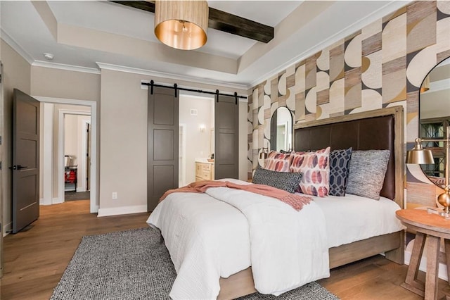 bedroom featuring a barn door, wood finished floors, baseboards, and a tray ceiling