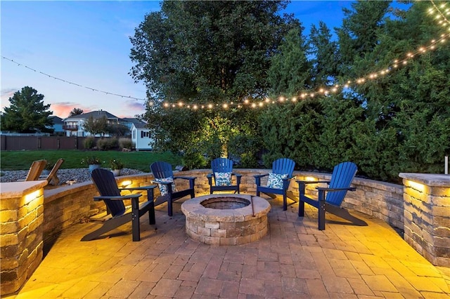 patio terrace at dusk with a fire pit and a lawn