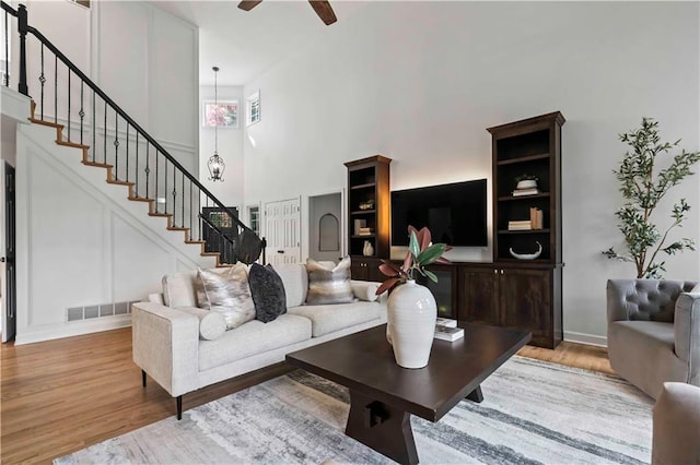 living area with stairs, ceiling fan, wood finished floors, and visible vents