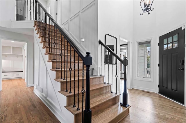 entrance foyer featuring an inviting chandelier, wood finished floors, a towering ceiling, and baseboards