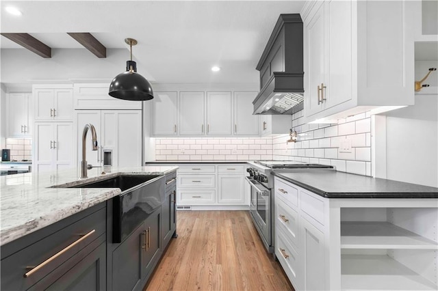 kitchen featuring open shelves, white cabinets, a sink, premium range hood, and high end range