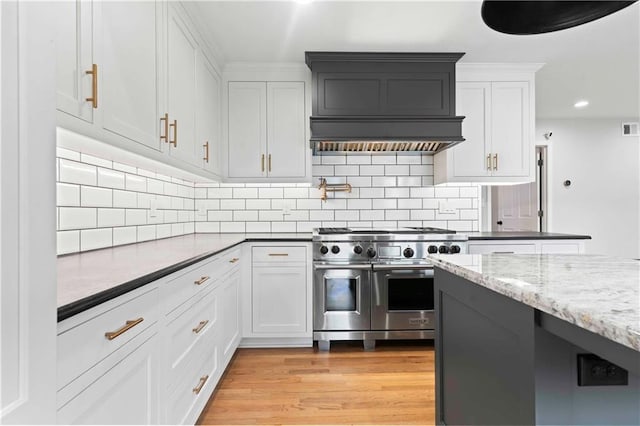 kitchen with visible vents, white cabinetry, double oven range, light wood-type flooring, and decorative backsplash