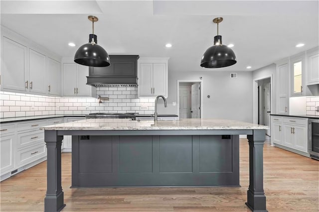 kitchen featuring light wood-style floors, a sink, backsplash, and a kitchen breakfast bar