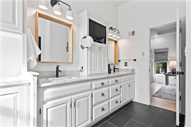 full bath with double vanity, visible vents, a sink, tile patterned flooring, and baseboards