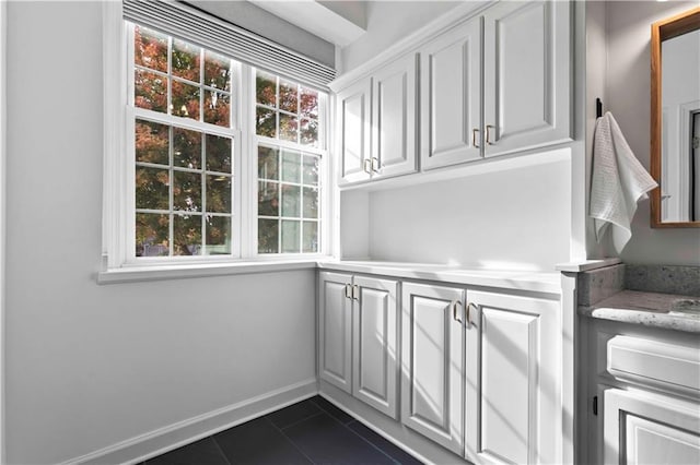 interior space with dark tile patterned floors and baseboards