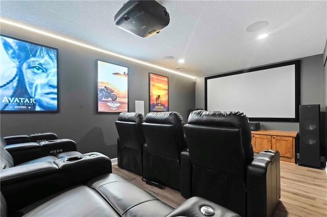 home theater room featuring light wood-style flooring, a textured ceiling, and recessed lighting