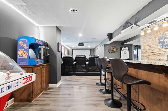 interior space featuring a dry bar, wood finished floors, visible vents, and baseboards