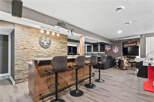 bar featuring light wood finished floors, visible vents, and indoor bar