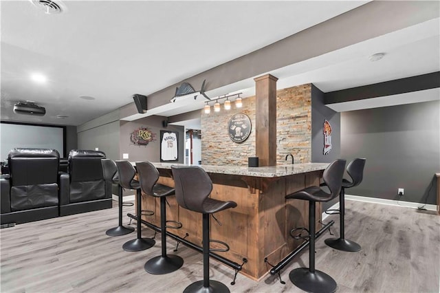 bar with light wood-style floors, indoor wet bar, visible vents, and baseboards