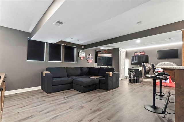 living room with light wood-type flooring, beam ceiling, visible vents, and baseboards