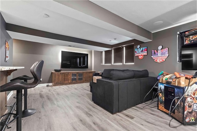 living area with light wood-style floors, baseboards, and beamed ceiling