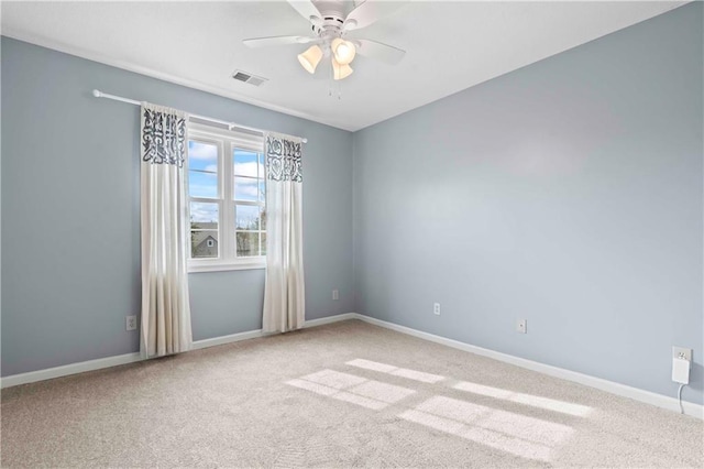 empty room with a ceiling fan, carpet flooring, visible vents, and baseboards