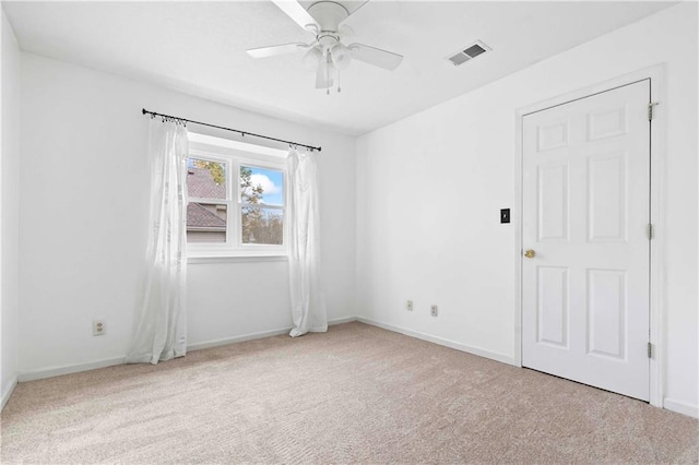 carpeted empty room featuring a ceiling fan, visible vents, and baseboards