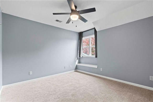 carpeted spare room with visible vents, ceiling fan, and baseboards