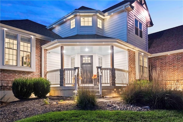 property entrance featuring a porch and brick siding