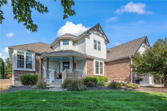 victorian home with covered porch, roof with shingles, brick siding, and a front lawn