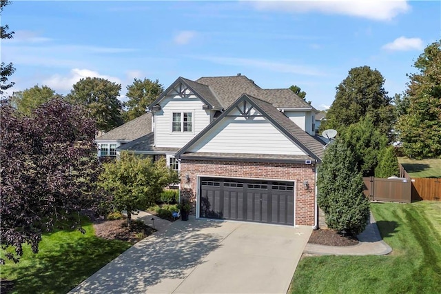 view of front of property featuring driveway, brick siding, a front lawn, and fence