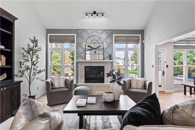 living area featuring light wood-type flooring, a fireplace, baseboards, and lofted ceiling