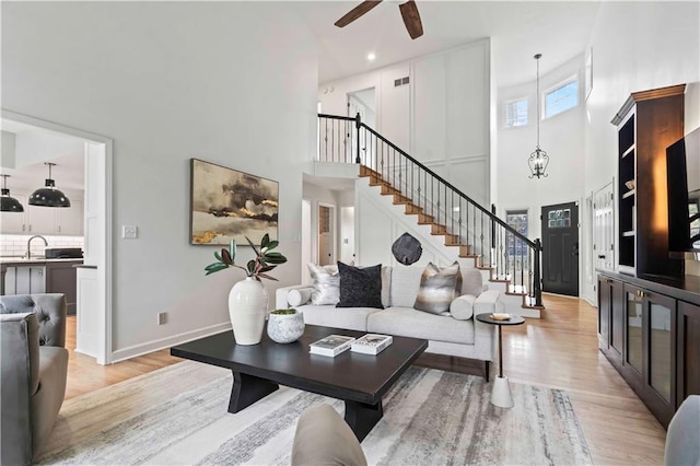 living area featuring light wood-type flooring, visible vents, stairway, and baseboards