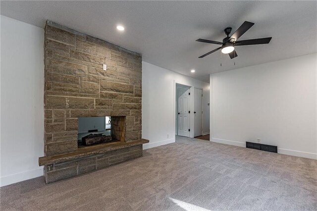 unfurnished living room with carpet floors, a stone fireplace, and ceiling fan