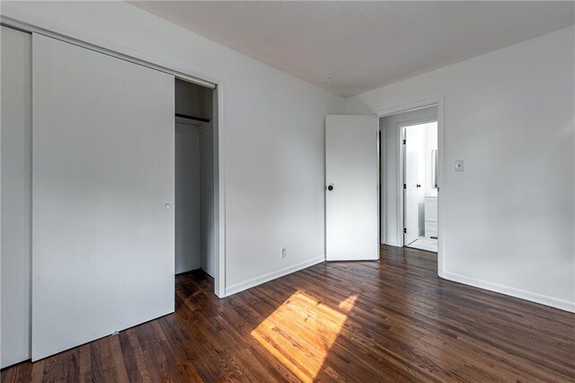 unfurnished bedroom featuring a closet and dark wood-type flooring