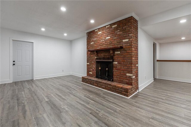 unfurnished living room featuring light hardwood / wood-style flooring and a brick fireplace