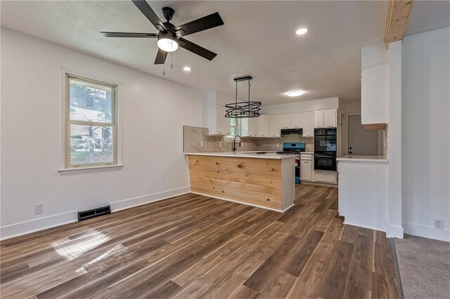 kitchen featuring hanging light fixtures, white cabinets, kitchen peninsula, stove, and ceiling fan