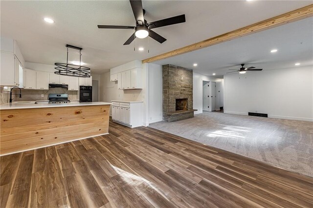 kitchen with ceiling fan, white cabinetry, stainless steel range oven, a fireplace, and dark hardwood / wood-style flooring