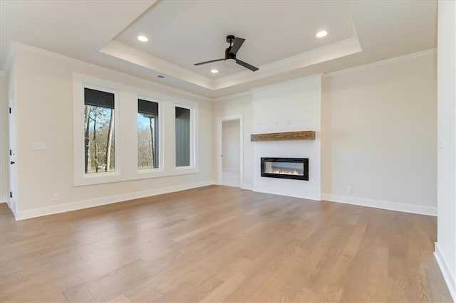 unfurnished living room with crown molding, a raised ceiling, and a large fireplace