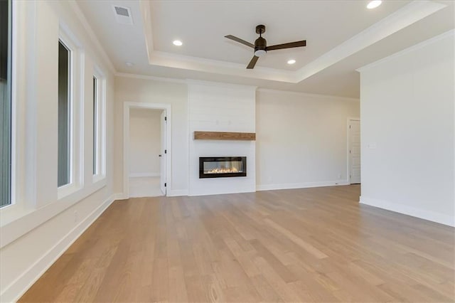 unfurnished living room featuring a raised ceiling, a large fireplace, and light wood-style flooring