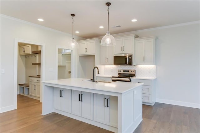 kitchen with backsplash, appliances with stainless steel finishes, a kitchen island with sink, a sink, and white cabinetry