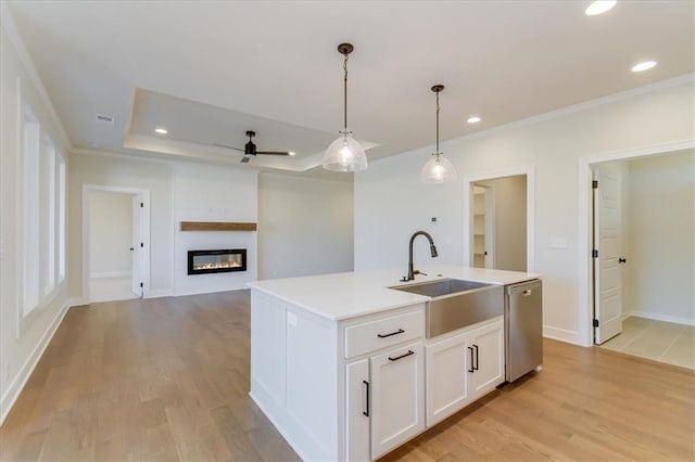 kitchen with a sink, light wood-style floors, a large fireplace, and dishwasher